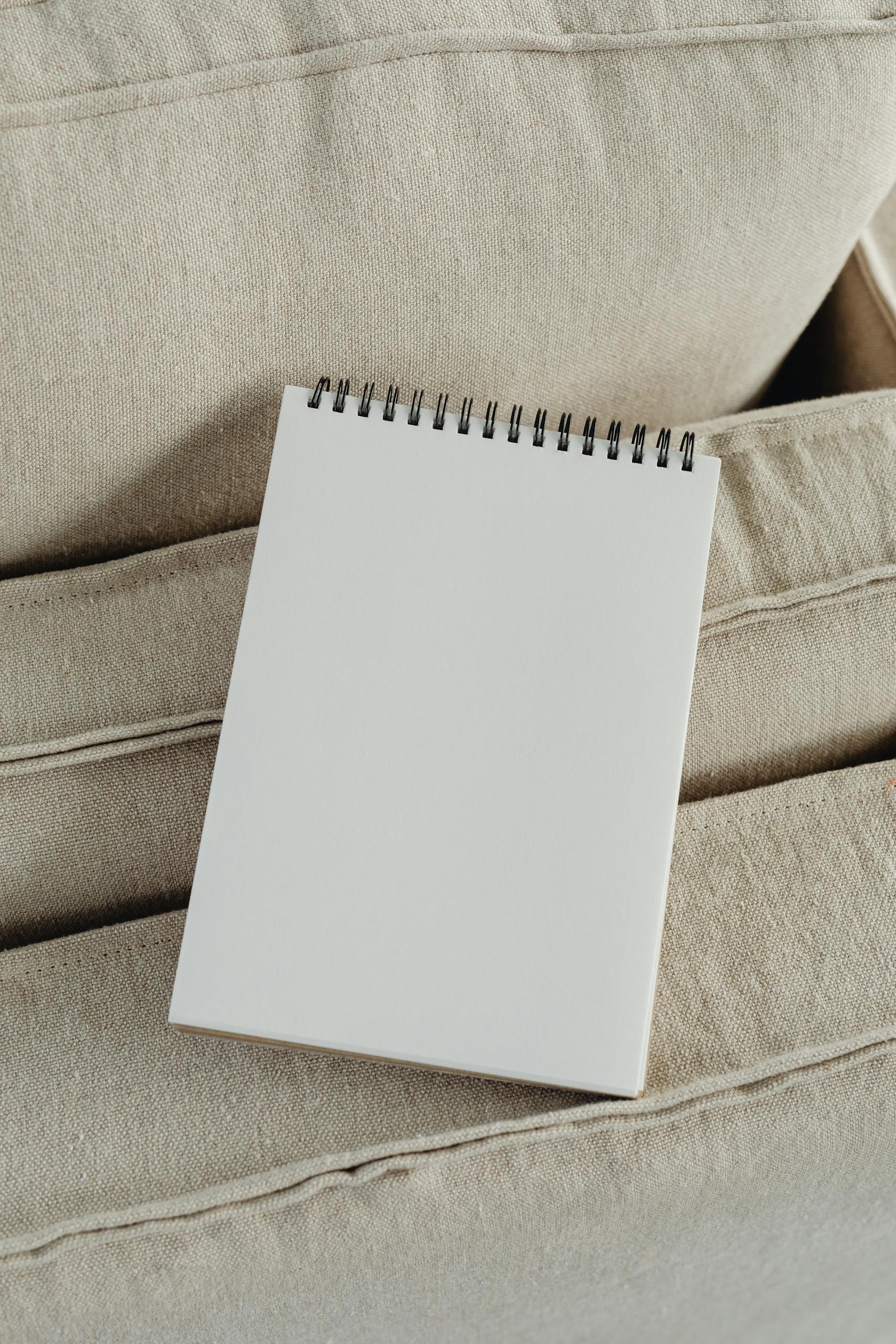 Empty spiral notepad resting on beige cushions, ideal for mockup or design presentations.